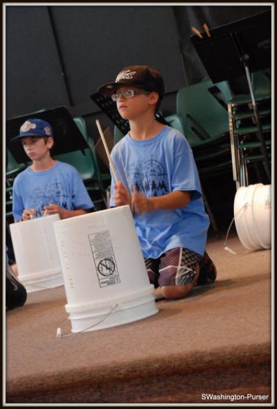 Campers performing bucket drumming as part of the final Junior Music Camp Concert