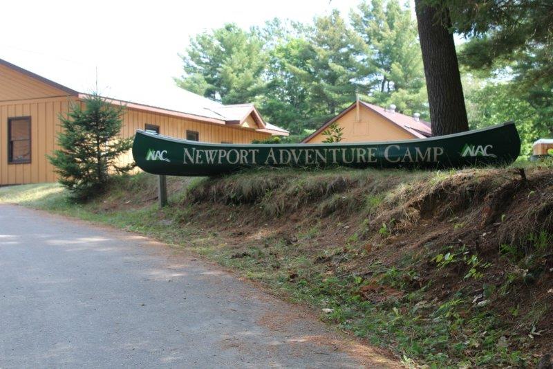 Newport Adventure Camp driveway. Green canoe with words Newport Adventure sitting on the top of the driveway