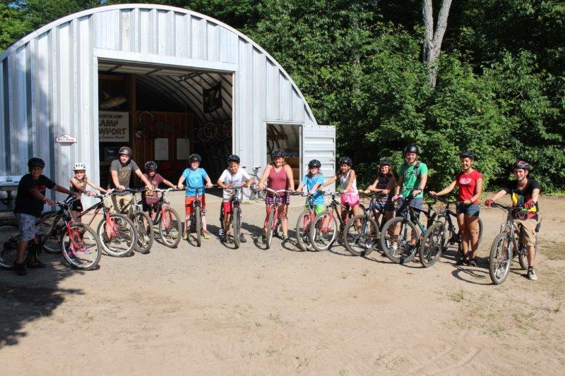 Mountain Biking Elective group posing with their bikes and helmets in front of the Bike Shop