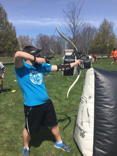 Teen standing behind an inflatable bunker while preparing to shoot an arrow