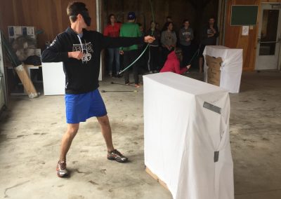 Teen shooting an arrow from behind a bunker in indoor archery tag